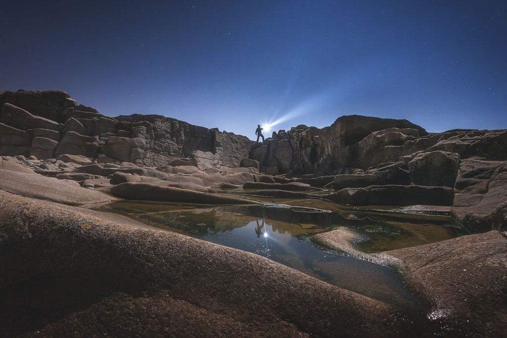 Homme avec une lampe torche dans un univers rocheux